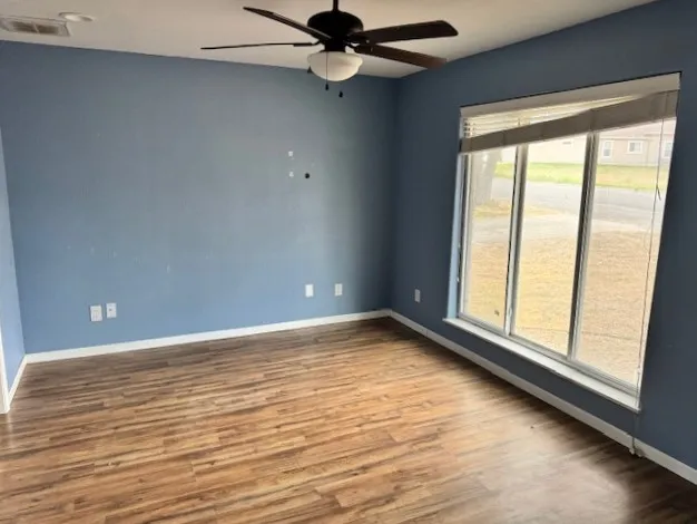 a view of an empty room with a window and wooden floor