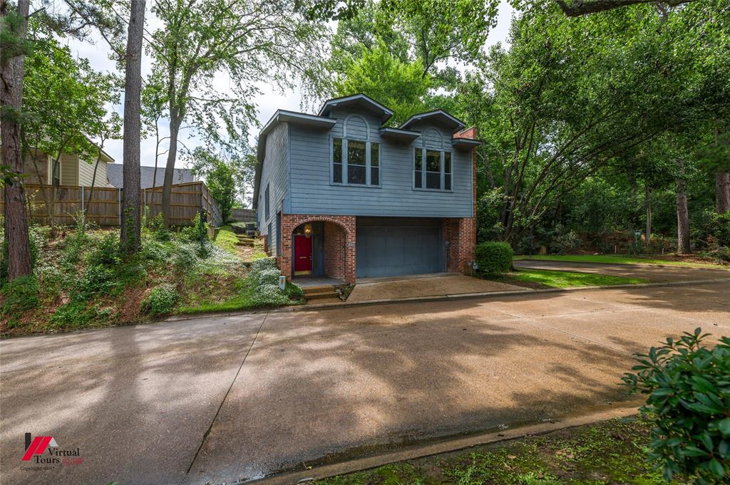 300 Pierremont Road, Unit 40 Shreveport, LA 71106 - Photo 2 of 34 Split-level residence featuring a prominent garage, a red entry door, and a light blue siding exterior