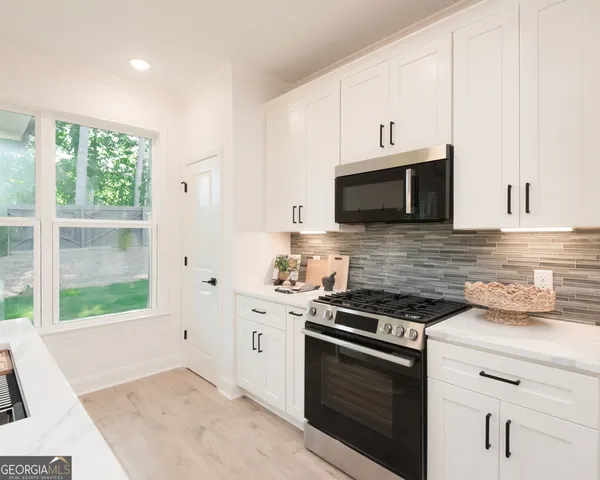 a kitchen with stainless steel appliances white cabinets and a stove top oven