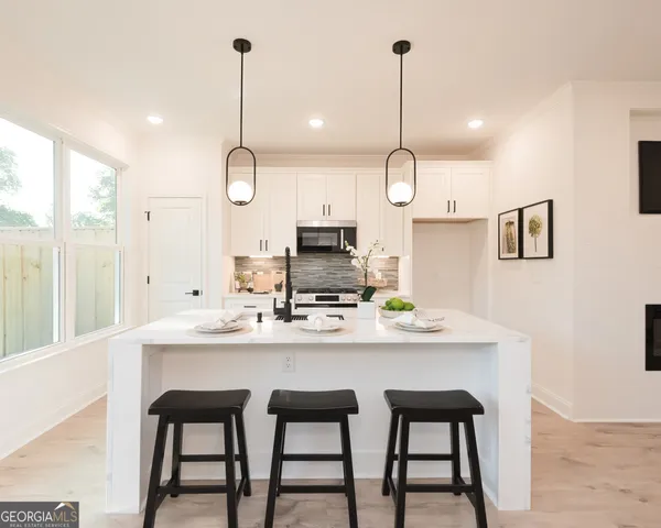 a kitchen with kitchen island a dining table chairs a sink and cabinets