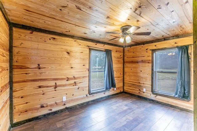 a view of a livingroom with wooden floor a ceiling fan and window