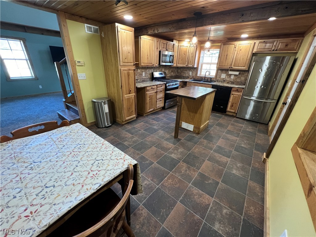Kitchen with a center island, sink, tasteful backsplash, hanging light fixtures, and stainless steel appliances