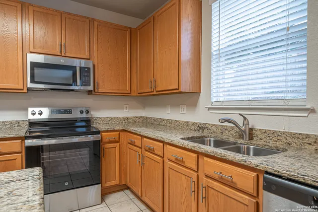 a kitchen with granite countertop cabinets stainless steel appliances and a sink