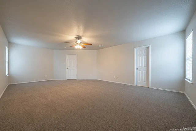 a view of an empty room with a chandelier fan