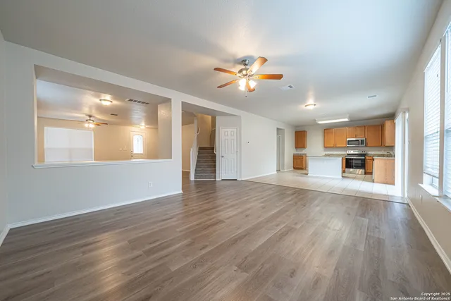 a view of an empty room with kitchen and window