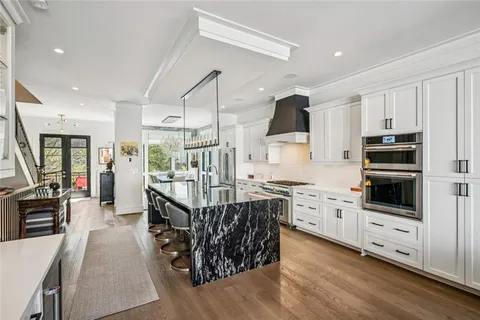 a kitchen with stainless steel appliances kitchen island granite countertop a stove top oven a sink dishwasher a refrigerator and a dining table with wooden floor