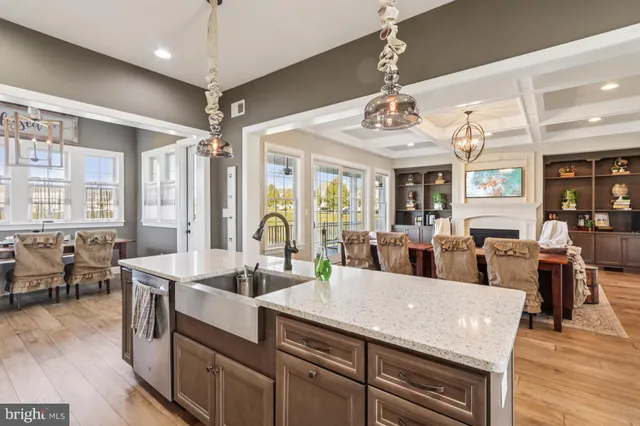 a kitchen with granite countertop a table chairs stove and white cabinets with wooden floor