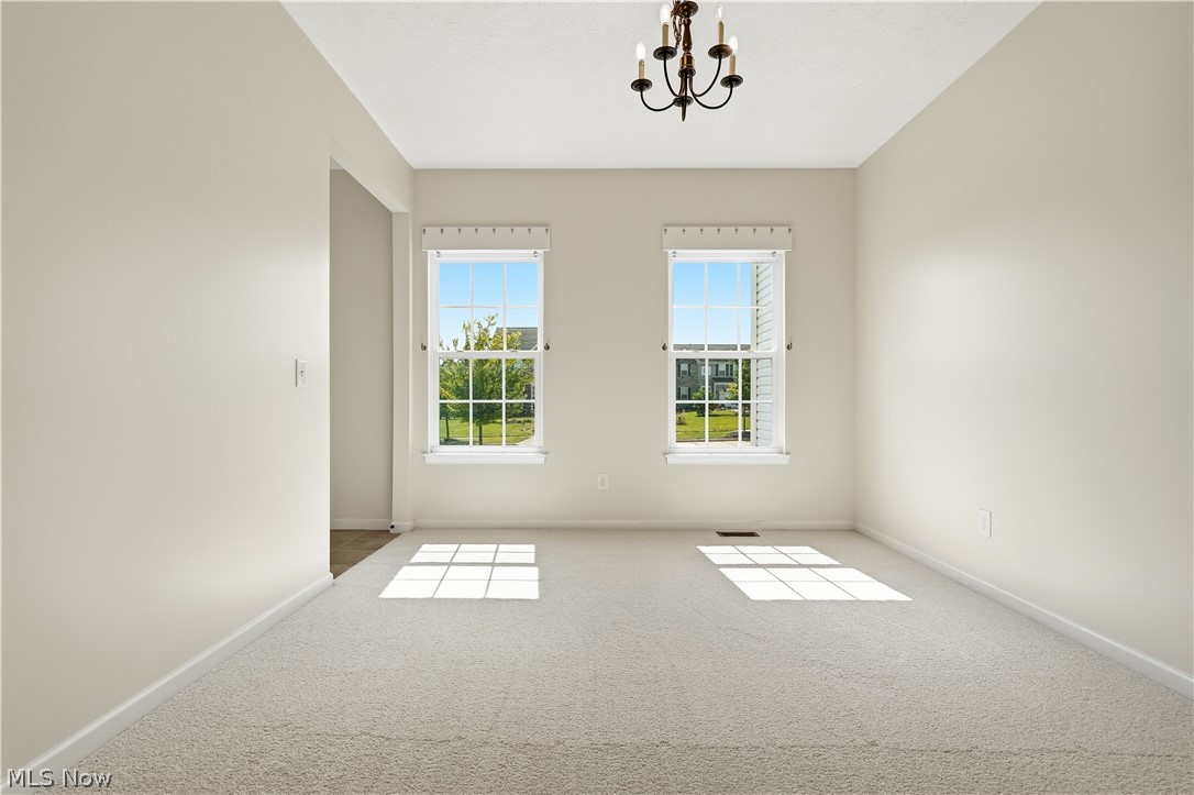 3280 Seven Bridges Road Medina, OH 44256 - Photo 19 of 41 Carpeted room featuring two windows with white blinds, a bronze chandelier, and light neutral wall finishes