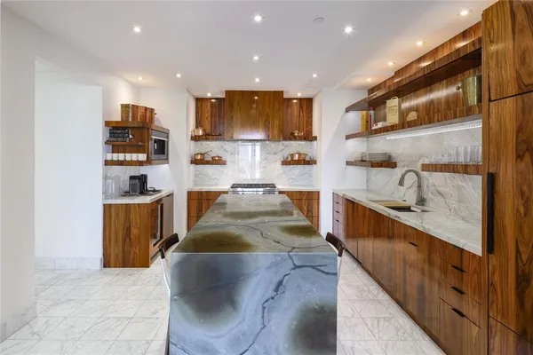 a large kitchen with kitchen island a sink a counter top space stainless steel appliances and cabinets