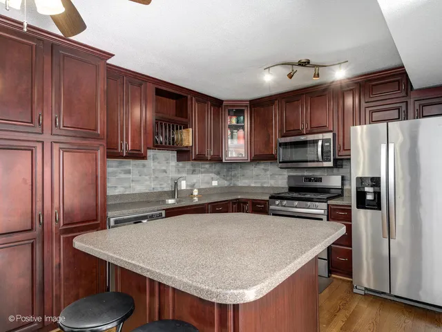 a kitchen with kitchen island granite countertop wooden cabinets stainless steel appliances and a counter space