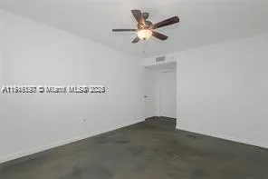 an empty room with a chandelier fan and a ceiling fan