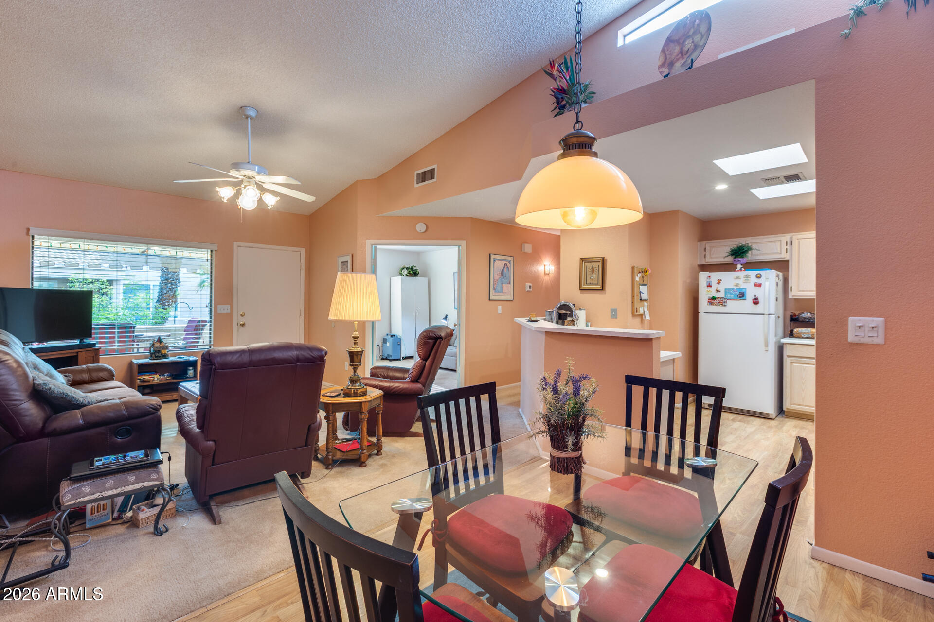 14300 West Bell Road, Unit 482 Surprise, AZ 85374 - Photo 9 of 53 a dining room with wooden floor a chandelier fan a wooden table and chairs