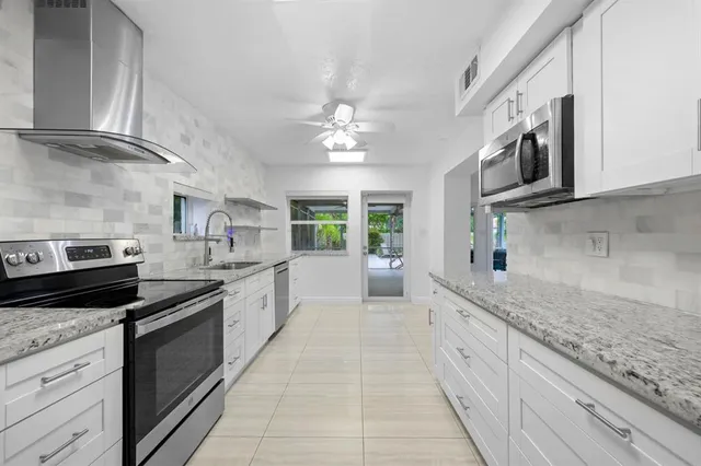 a large kitchen with stainless steel appliances granite countertop a stove and a sink