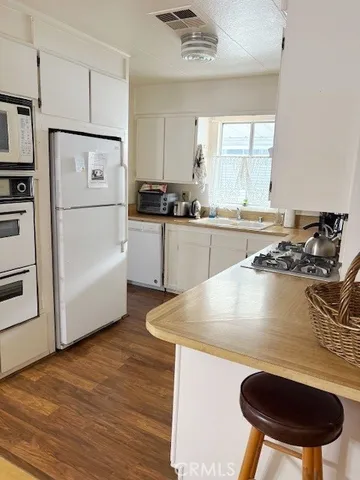 a kitchen with stainless steel appliances granite countertop a sink a stove a refrigerator and white cabinets