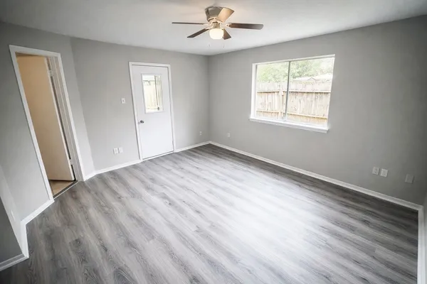 a view of an empty room with wooden floor and a window