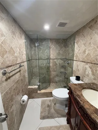 a bathroom with a granite countertop sink a toilet a mirror and shower