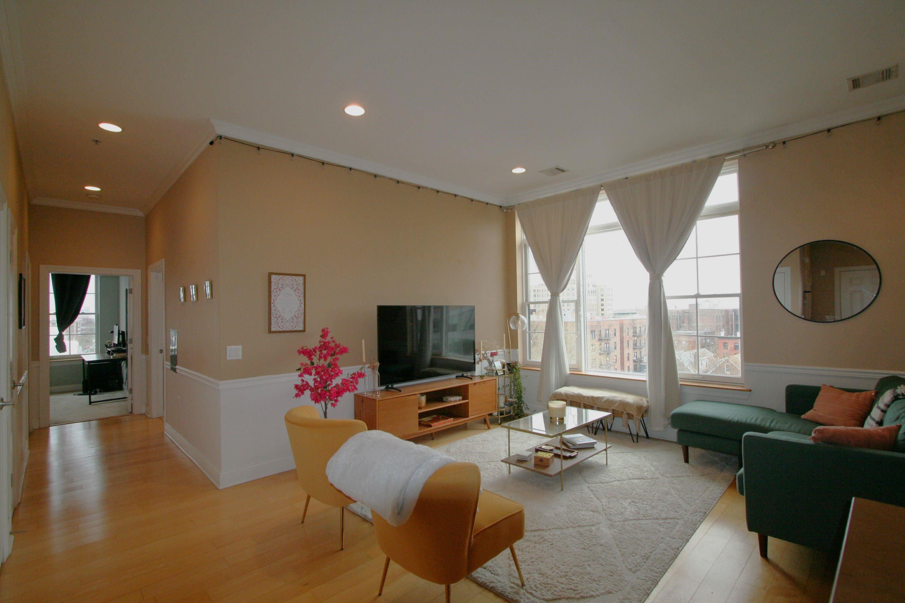 a living room with furniture flat screen tv and a large window