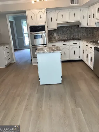 a kitchen with stainless steel appliances granite countertop a stove a sink and white cabinets