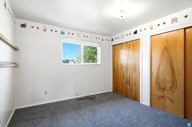 2252 West 800 North Clinton, UT 84015 - Photo 17 of 38 Carpeted room featuring a double window, two wooden sliding closet doors, and built-in wall shelving