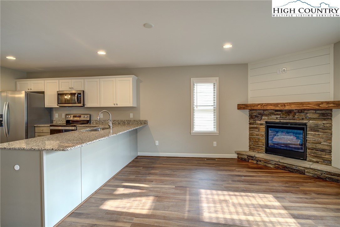 142 Casey Overlook Lane, Unit 82 Boone, NC 28607 - Photo 19 of 43 a large kitchen with granite countertop a stove top oven a sink dishwasher and a refrigerator with wooden floor