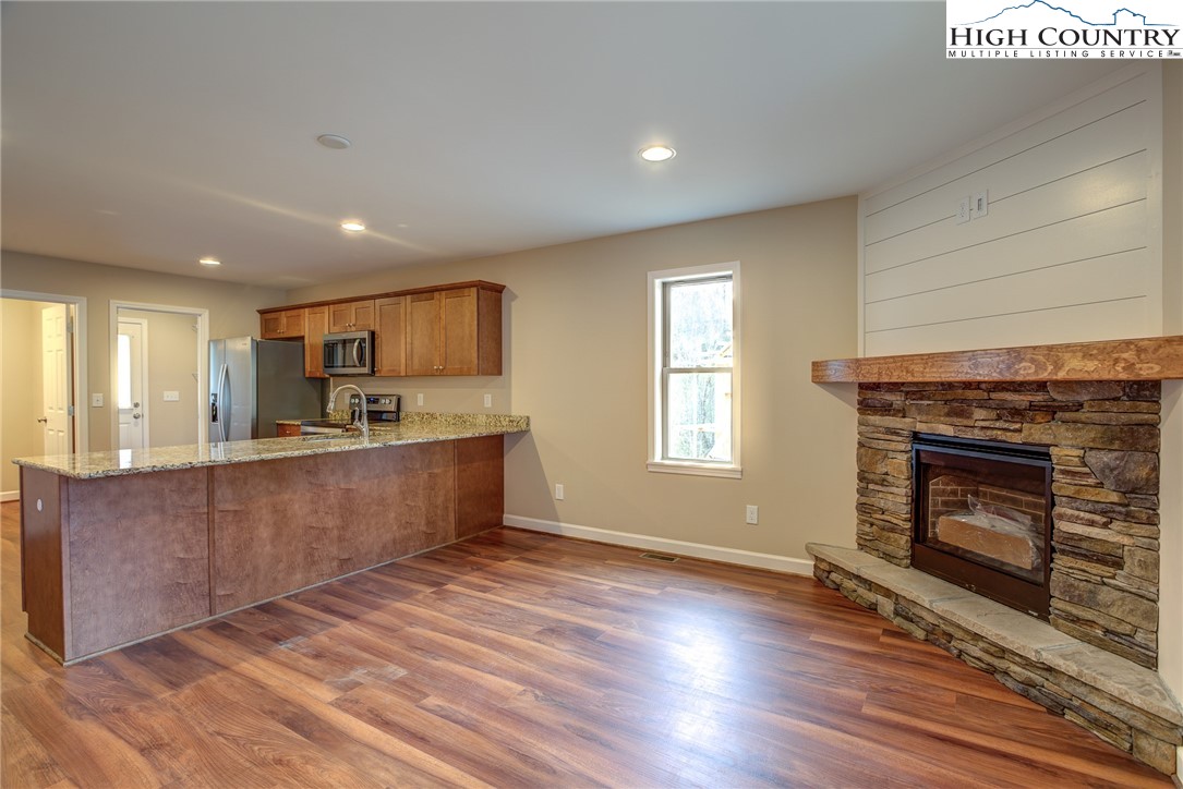 142 Casey Overlook Lane, Unit 82 Boone, NC 28607 - Photo 21 of 43 a kitchen with stainless steel appliances granite countertop a stove top oven a sink dishwasher and a fireplace with wooden floor