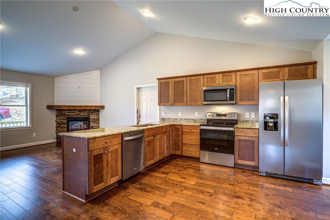 142 Casey Overlook Lane, Unit 82 Boone, NC 28607 - Photo 23 of 43 a kitchen with stainless steel appliances granite countertop a stove top oven a sink dishwasher a refrigerator and a microwave oven with large wooden floor