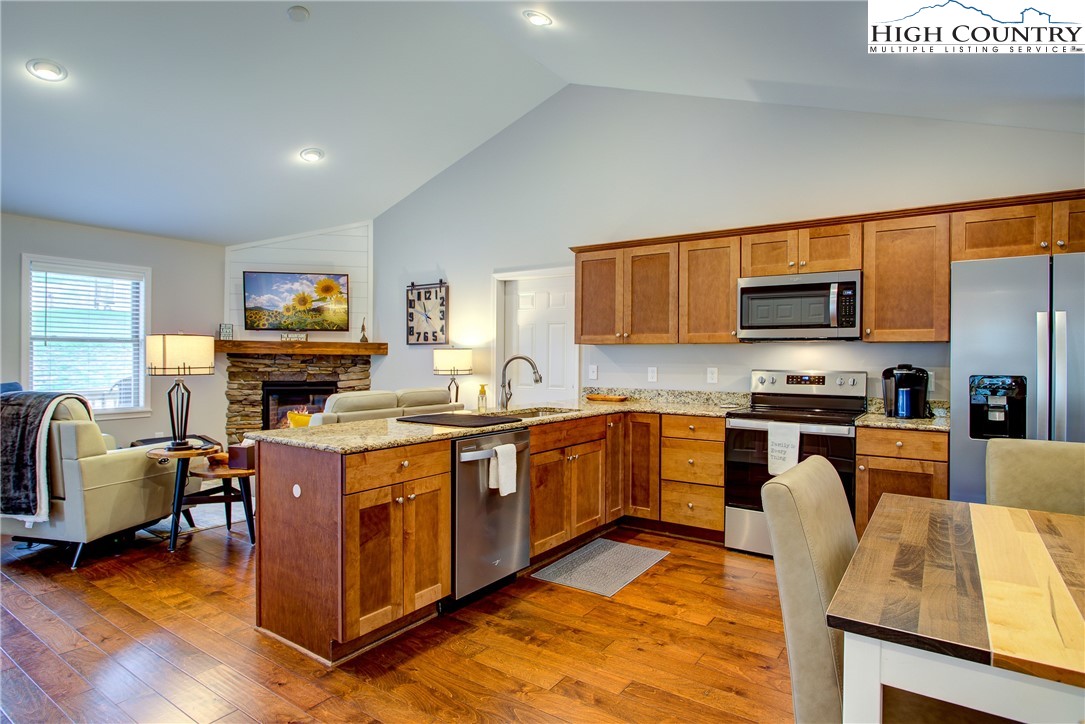 142 Casey Overlook Lane, Unit 82 Boone, NC 28607 - Photo 7 of 43 a kitchen with stainless steel appliances granite countertop a stove top oven a sink dishwasher a dining table and chairs with wooden floor