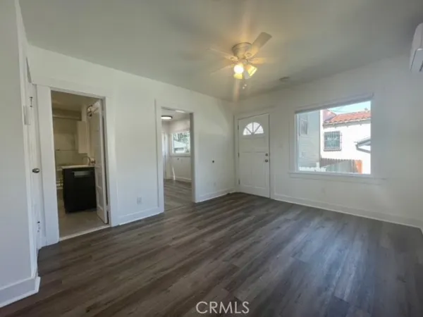 a view of an empty room with wooden floor and a window