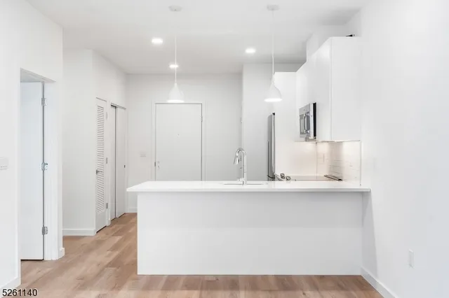 a view of a kitchen with kitchen island a sink stainless steel appliances and cabinets
