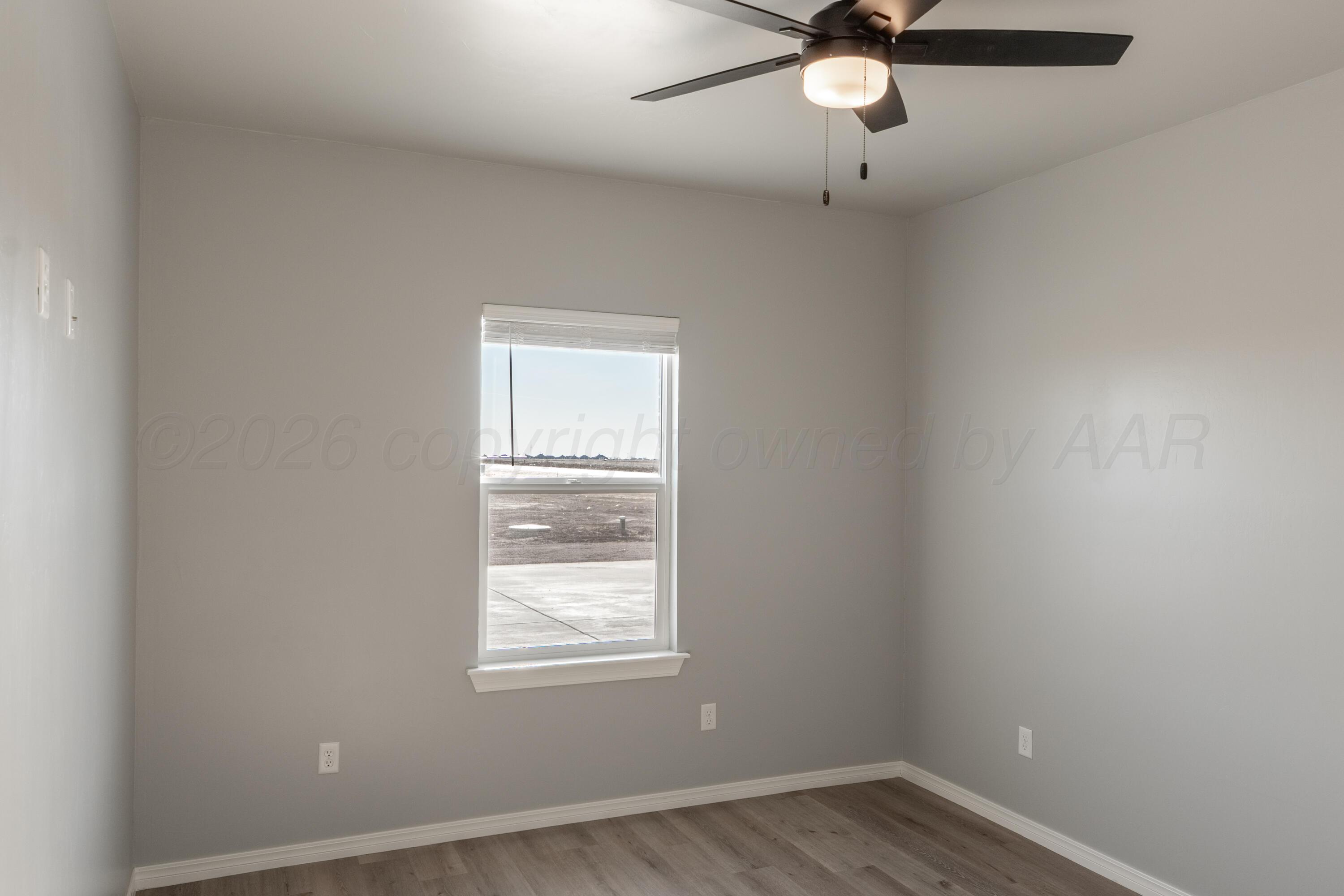 11074 Verano Drive Amarillo, TX 79119 - Photo 12 of 15 an empty room with wooden floor fan and windows