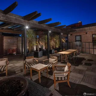 a view of a patio with a dining table and chairs under an umbrella with a barbeque grill and couches