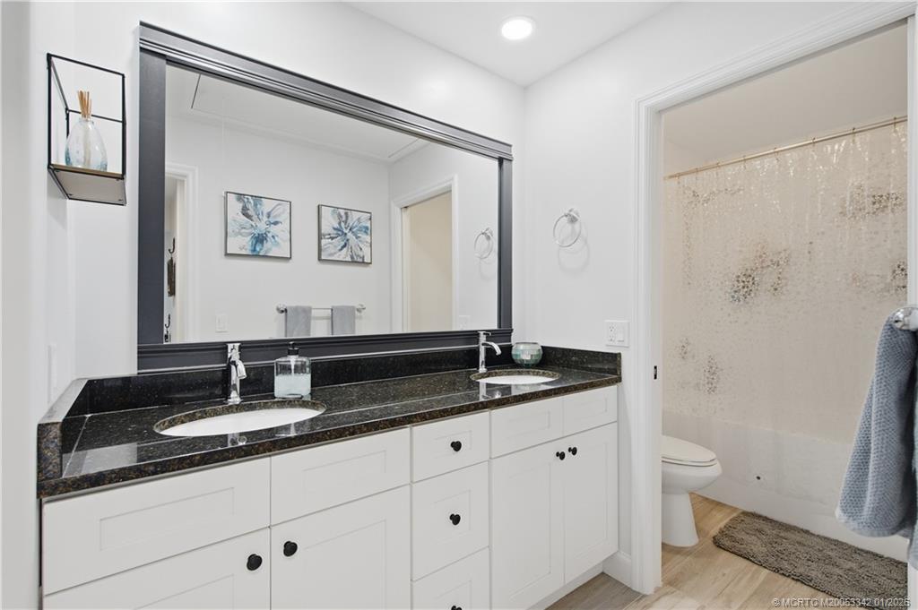 3584 Southwest Sunset Trace Circle Palm City, FL 34990 - Photo 21 of 32 a bathroom with a granite countertop sink a toilet and a mirror