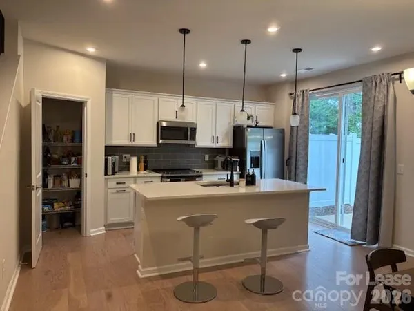 a kitchen with kitchen island stainless steel appliances a stove a refrigerator a sink cabinets and wooden floor