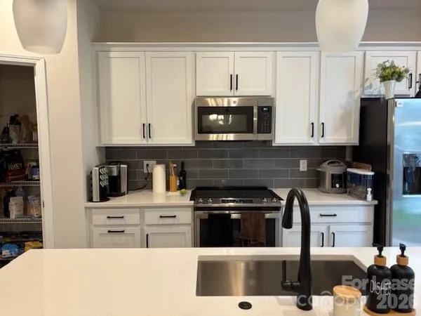 a kitchen with stainless steel appliances a stove a microwave a sink and cabinets