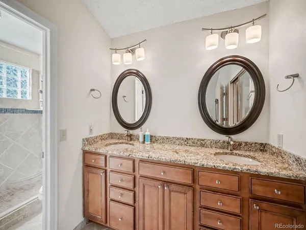 a bathroom with a granite countertop double vanity sink and a mirror