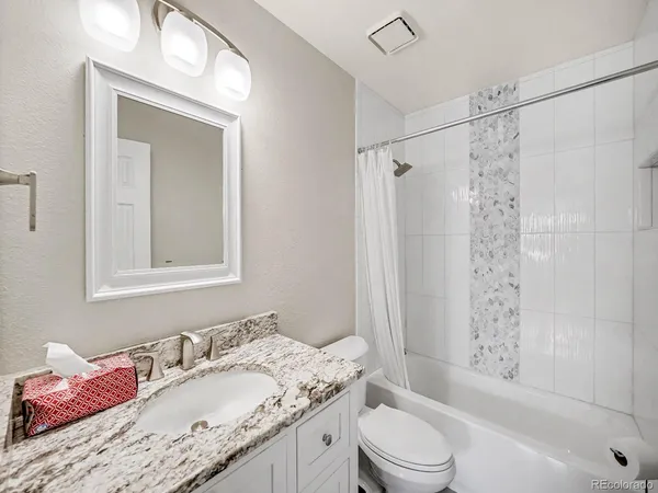 a bathroom with a granite countertop sink toilet a mirror and shower