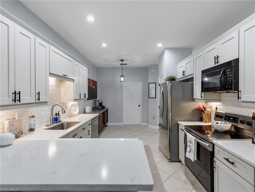 20334 Larino Loop Estero, FL 33928 - Photo 11 of 39 a kitchen with stainless steel appliances a refrigerator a sink a stove top oven a counter space and cabinets