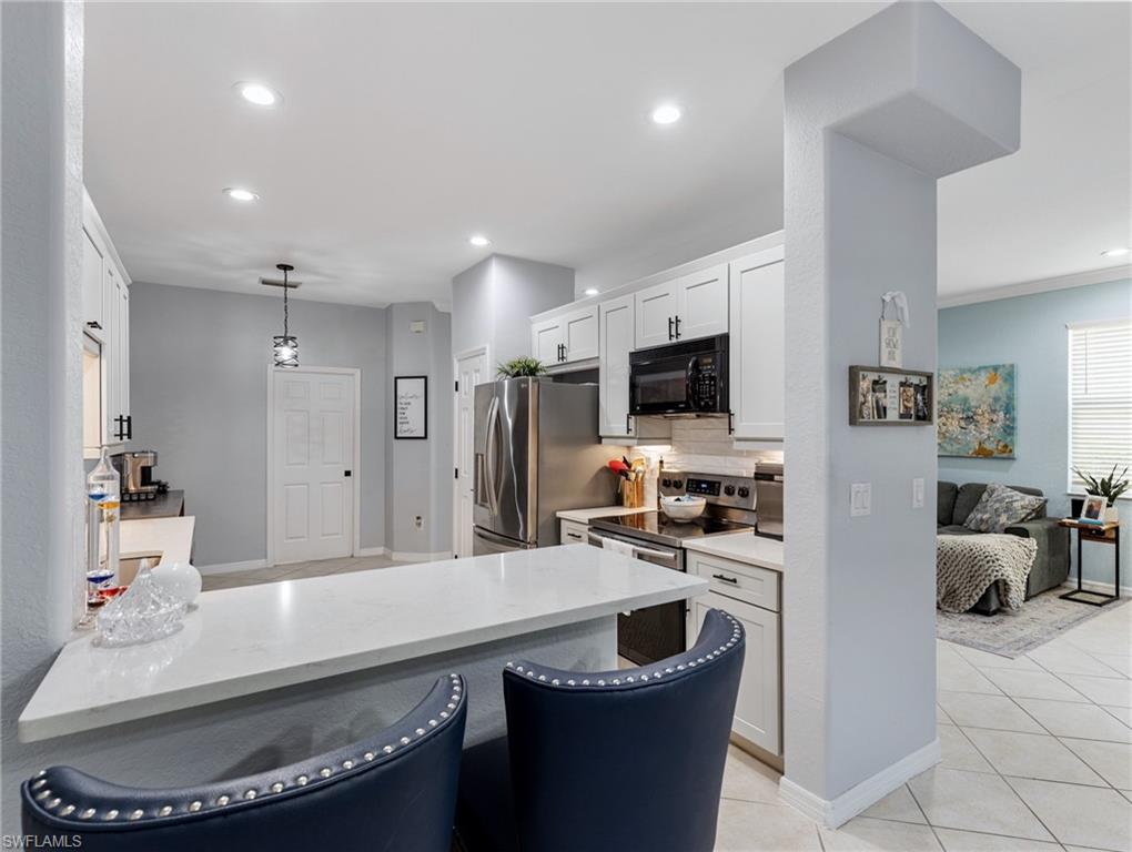 20334 Larino Loop Estero, FL 33928 - Photo 13 of 39 a kitchen with stainless steel appliances granite countertop a sink a stove a refrigerator a microwave a refrigerator and white cabinets