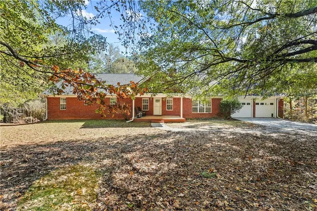 a backyard of a house with large trees and wooden fence
