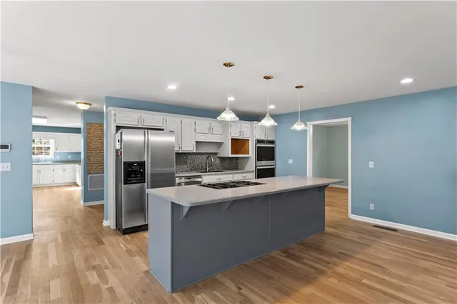 a large kitchen with stainless steel appliances a large counter top and a refrigerator