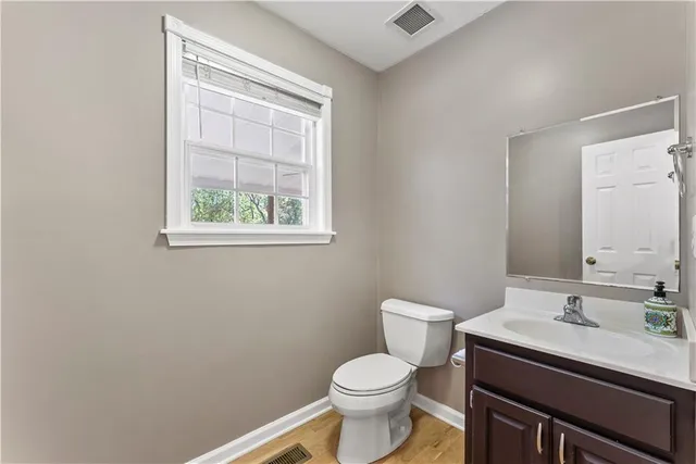 a bathroom with a granite countertop toilet a sink a mirror and a window