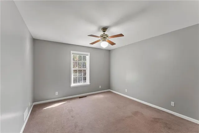 an empty room with a window and a ceiling fan