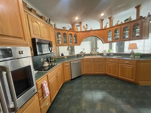 a kitchen with stainless steel appliances granite countertop a refrigerator a stove and a sink with wooden cabinets
