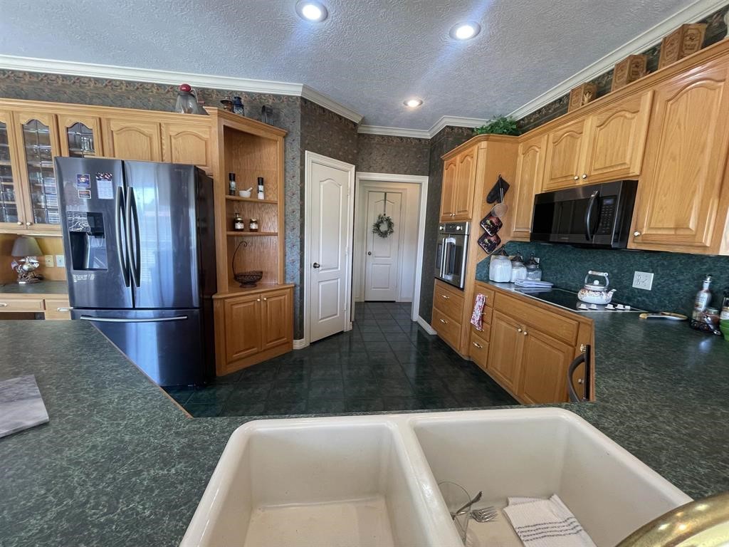 1655 Wooten Road Beaumont, TX 77707 - Photo 9 of 46 a kitchen with stainless steel appliances granite countertop a refrigerator a stove and a sink with wooden cabinets