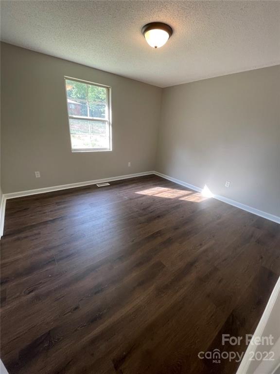 56 Barbee Road Southwest, Unit 1A Concord, NC 28027 - Photo 7 of 9 an empty room with wooden floor and windows