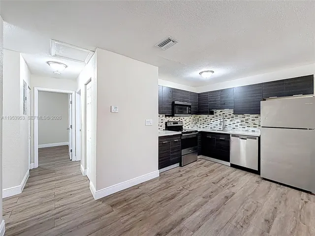 a kitchen with a refrigerator a stove top oven and wooden floor