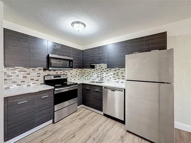 a kitchen with stainless steel appliances wooden floor sink stove and wooden floor