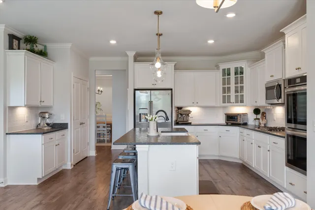 a kitchen with stainless steel appliances kitchen island granite countertop a sink stove and refrigerator