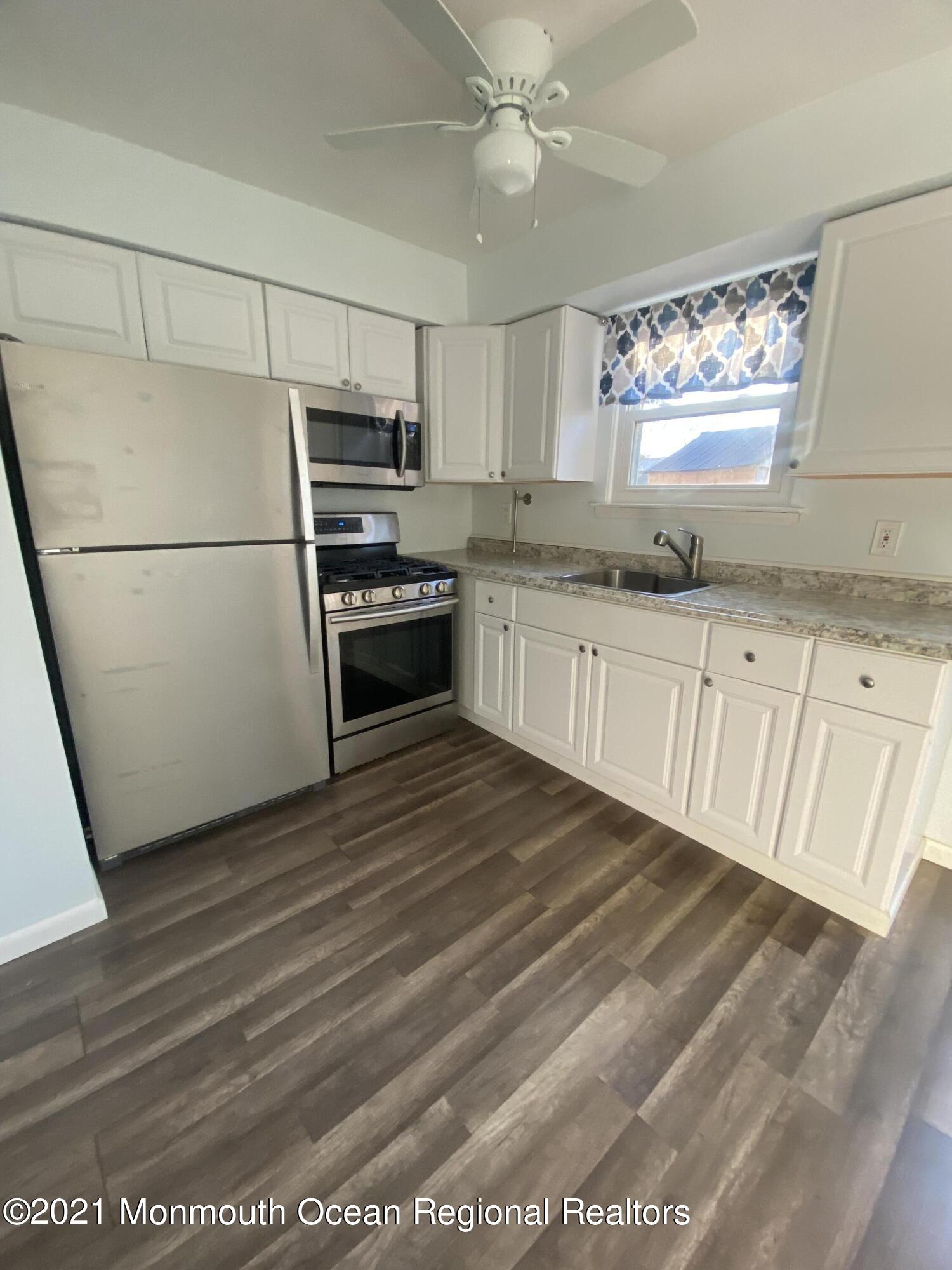 100 Greenwood Loop Road Brick, NJ 08724 - Photo 4 of 6 a kitchen with granite countertop a refrigerator a sink and white cabinets