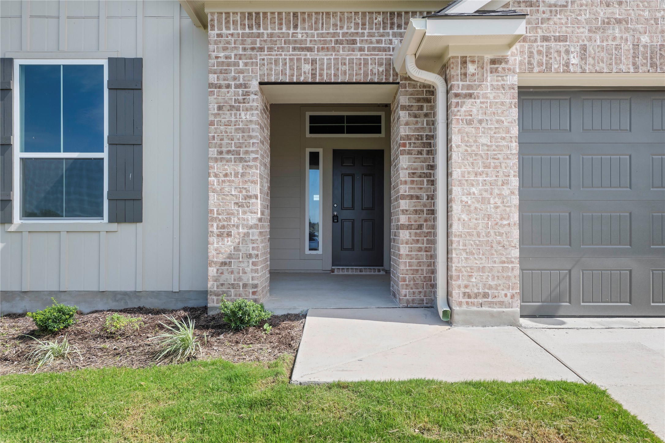 220 Gus Loop Georgetown, TX 78626 - Photo 2 of 18 A welcoming front entrance featuring brick and siding, complemented by a neatly landscaped bed and a functional garage.